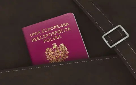 Nowy polski paszport w kolorze fuksji z godłem orła w złocie, schowany w brązowej skórzanej kieszeni.
