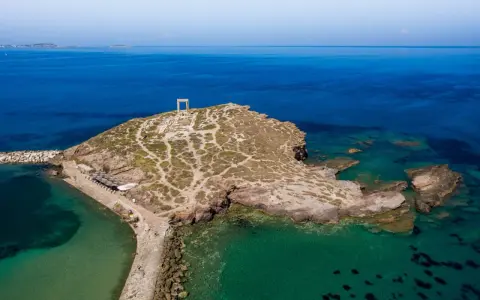 Portara, brama starożytnej świątyni Apollina, na skalistej wysepce. Największa wyspa Cyklad, Naksos, wita turystów.