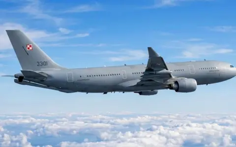 Szary samolot Airbus A330-300 z numerem 3301 i polską szachownicą na ogonie leci nad chmurami.
