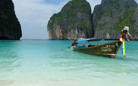 Łódź kołysze się na turkusowych wodach Maya Bay, otoczonej majestatycznymi klifami.