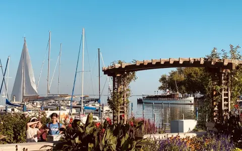 Trzy dziewczynki przyglądają się żaglówkom na jeziorze Balaton. W tle widać statek wycieczkowy.