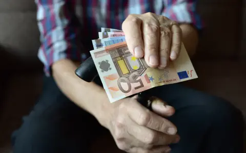 Dłoń trzyma banknoty euro, które są walutą Słowenii.