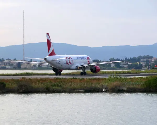 Samolot Czech Airlines na pasie startowym lotniska na Korfu, z wodą i zielenią w tle.