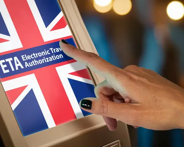 Dłoń dotyka ekranu z flagą Wielkiej Brytanii i napisem "ETA Electronic Travel Authorization".