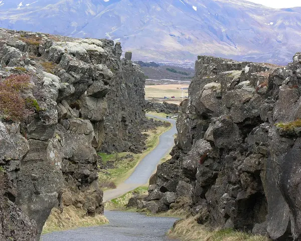Wąwóz w Parku Narodowym Þingvellir, część Złotego Kręgu Islandii. Kamienne ściany i droga wiodąca w głąb krajobrazu.