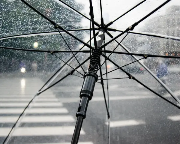Przezroczysty parasol w bagażu podręcznym chroni przed deszczem na ulicy. Krople wody na materiale.