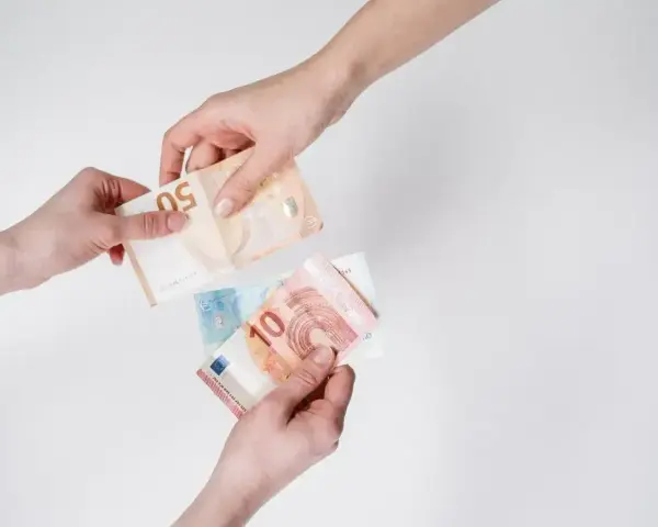 Dwie ręce przekazują sobie banknoty euro. To popularna waluta austrii, używana do codziennych transakcji.
