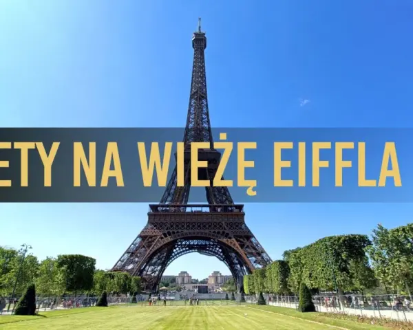 Wieża Eiffla w Paryżu, z napisem "Bilety na Wieżę Eiffla" na tle błękitnego nieba.