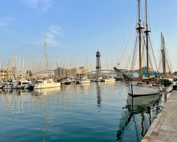 Port w Barcelonie, pełen żaglówek i statków, z wieżą widokową w tle. Czy w Barcelonie jest bezpiecznie? Tak, to spokojne miejsce.