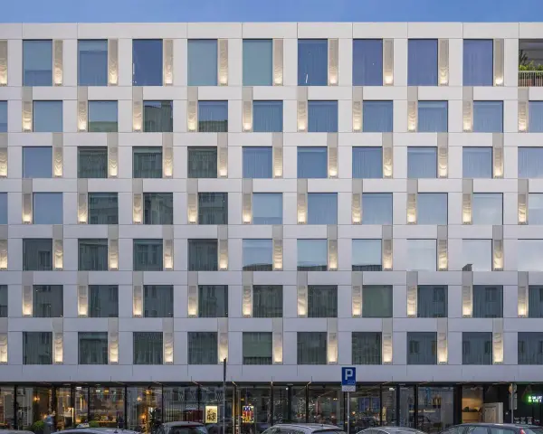 Nowoczesny hotel Puro Warszawa z licznymi oknami i pionowymi podświetlanymi elementami fasady.