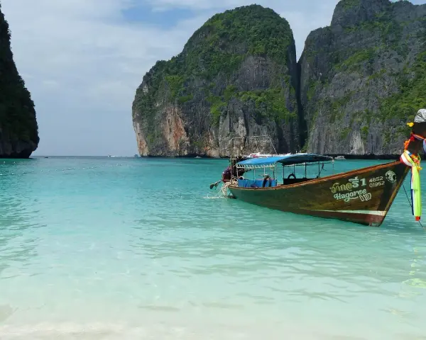 Łódź kołysze się na turkusowych wodach Maya Bay, otoczonej majestatycznymi klifami.