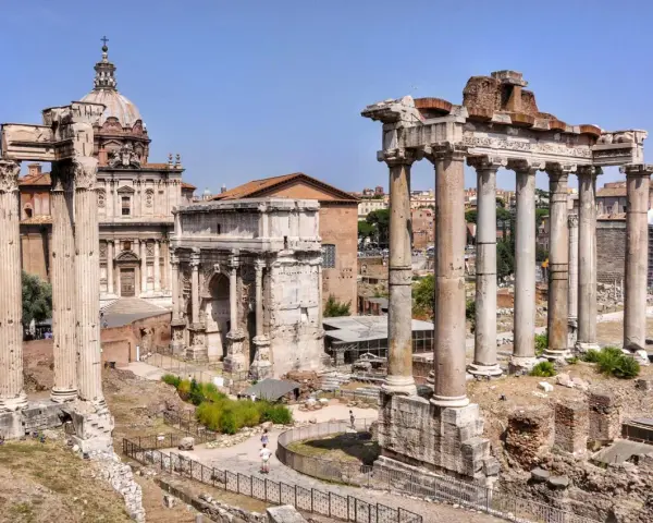 Wspaniały wyjazd do Rzymu! Ruiny Forum Romanum z łukiem i kolumnami na tle błękitnego nieba.