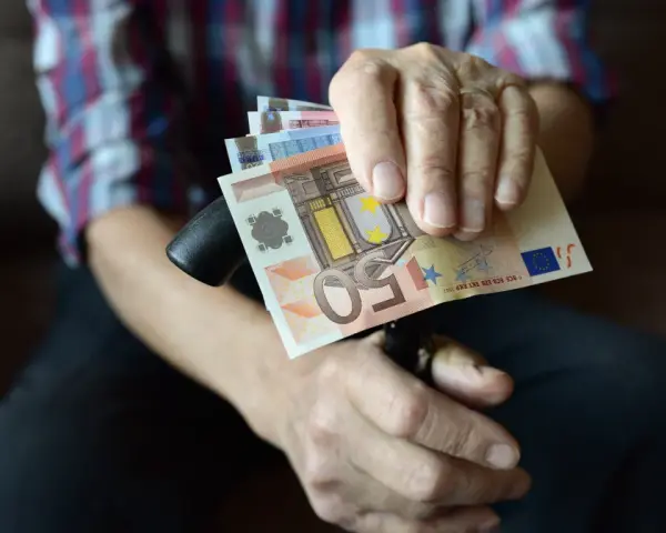Dłoń trzyma banknoty euro, które są walutą Słowenii.