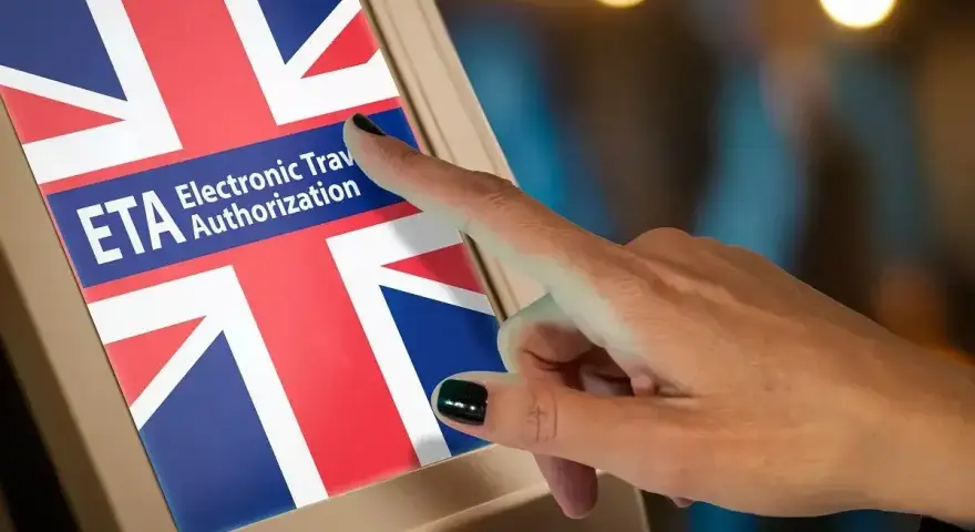 Dłoń dotyka ekranu z flagą Wielkiej Brytanii i napisem "ETA Electronic Travel Authorization". Czy do Londynu trzeba paszport? Sprawdź ETA.