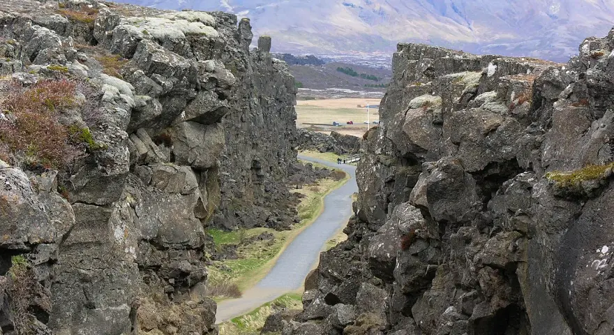 Wąwóz w Parku Narodowym Þingvellir, część Złotego Kręgu Islandii. Kamienne ściany i droga wiodąca w głąb krajobrazu.