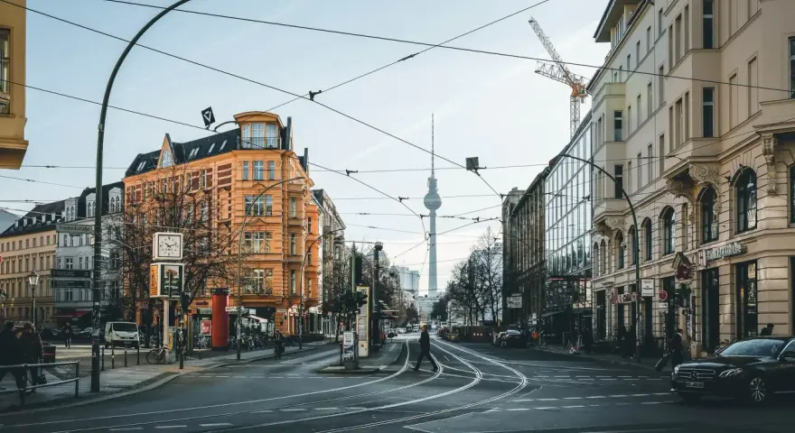 Skrzyżowanie w Berlinie z widoczną wieżą telewizyjną. Czy Berlin jest bezpieczny? Miasto tętni życiem, a ludzie swobodnie poruszają się po ulicach.