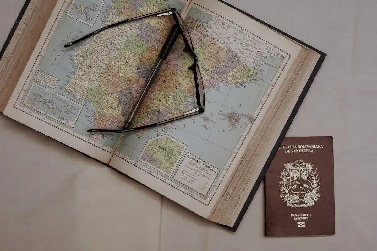 Otwarta księga z mapą Europy, okulary i paszport Wenezueli. Planujesz podróż? Eta co to za kraj?