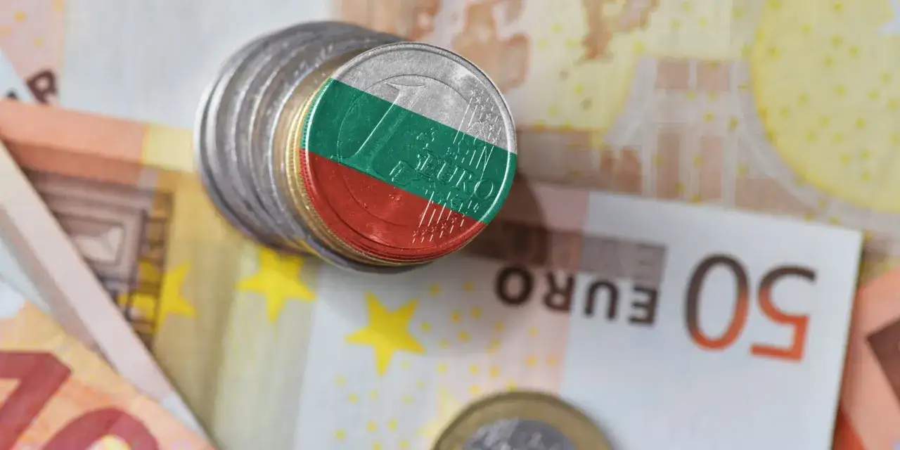 Monety z flagą Bułgarii na tle eurobanknotów. Waluta Bułgarii, lew, obok symboli Unii Europejskiej.