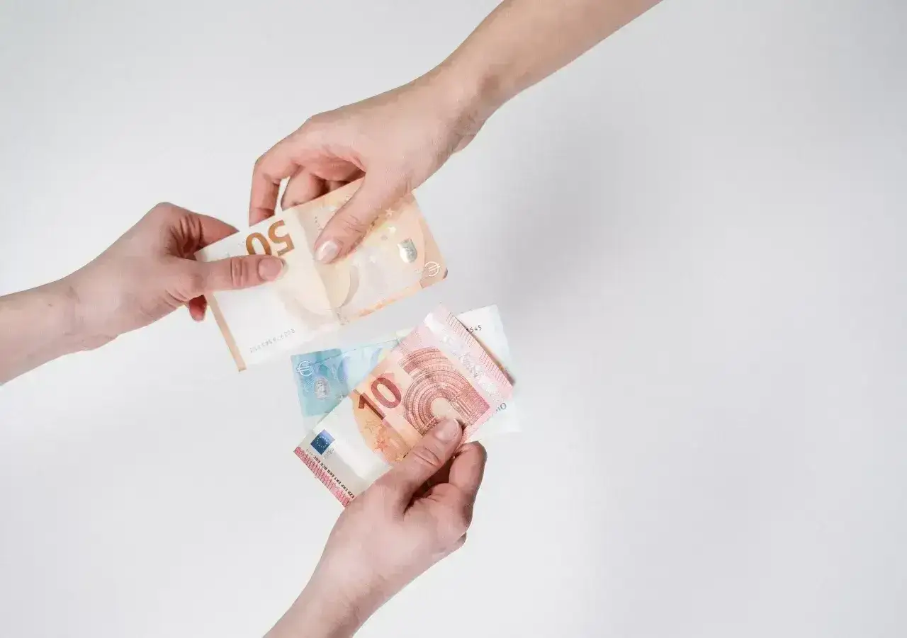 Dwie ręce przekazują sobie banknoty euro. To popularna waluta austrii, używana do codziennych transakcji.