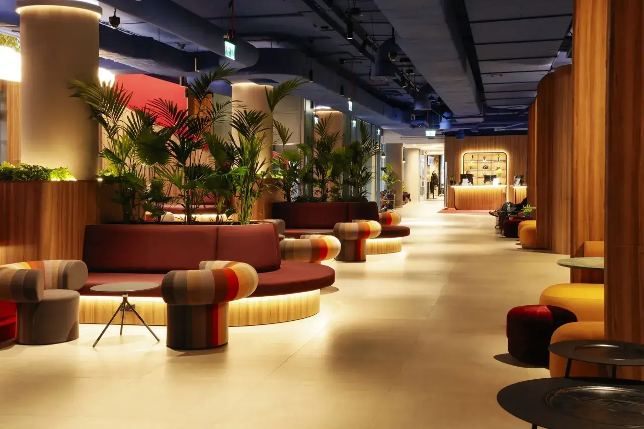 Nowoczesne wnętrze hotelu Mercure Warszawa Centrum z wygodnymi sofami, kolorowymi pufami i bujną roślinnością tworzy przytulną atmosferę.