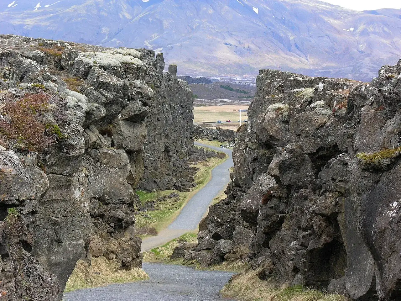 Wąwóz w Parku Narodowym Þingvellir, część złoty krąg Islandia. Droga wije się między skalnymi ścianami, w tle góry.