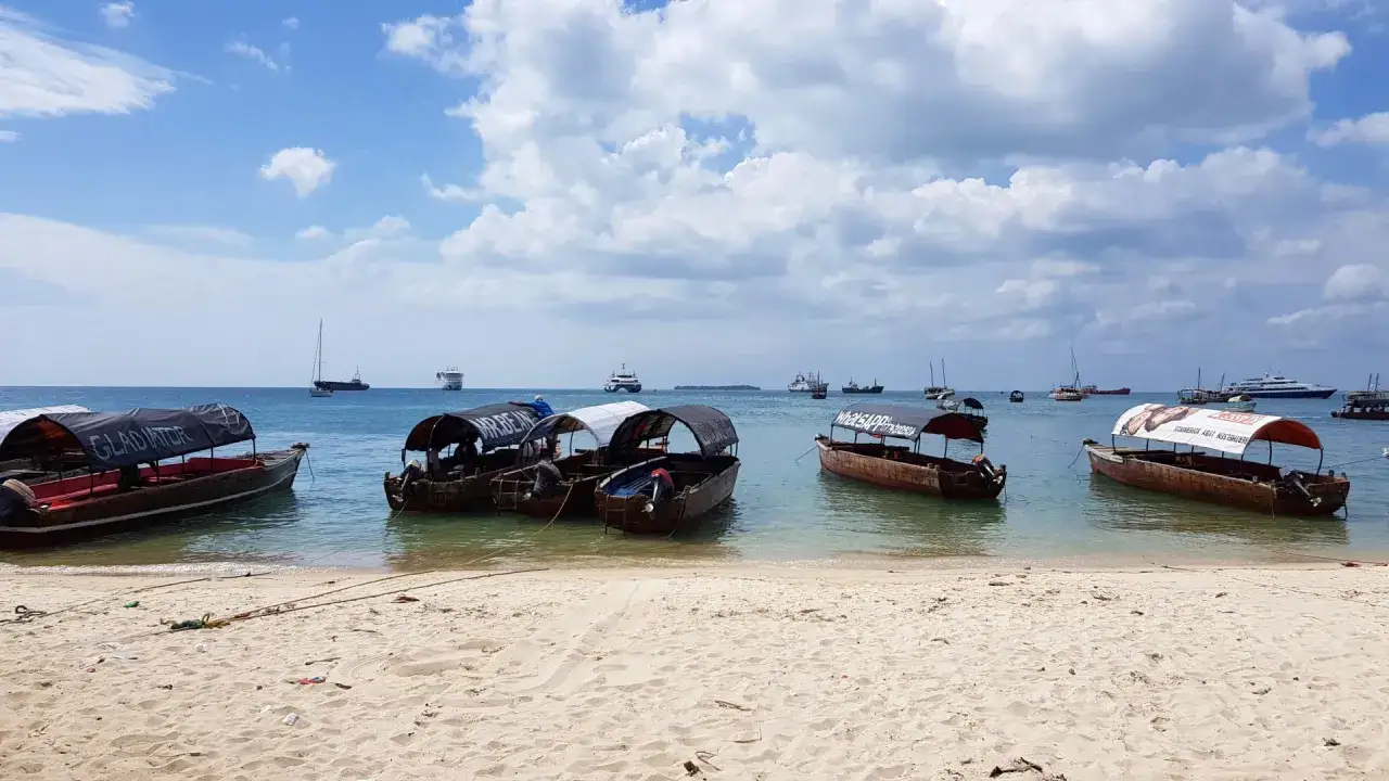 Łodzie na spokojnym morzu, w tle statki. Czy Zanzibar jest bezpieczny? Tak, to spokojne miejsce na wakacje.