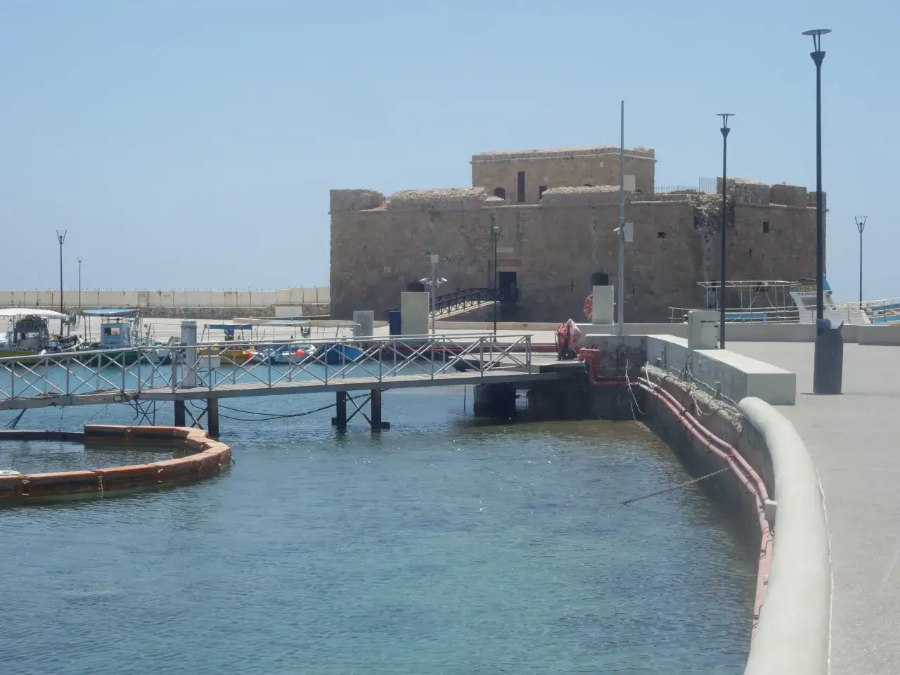 Kamienny zamek w Pafos, stare miasto, góruje nad portem z łodziami i pomostem.