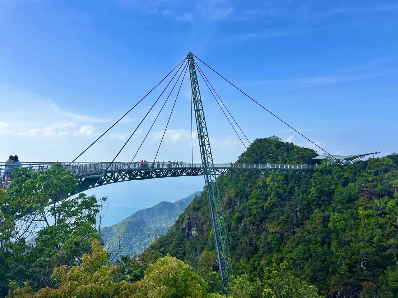 Wiszący most na wyspie Langkawi, otoczony bujną zielenią i widokiem na morze.