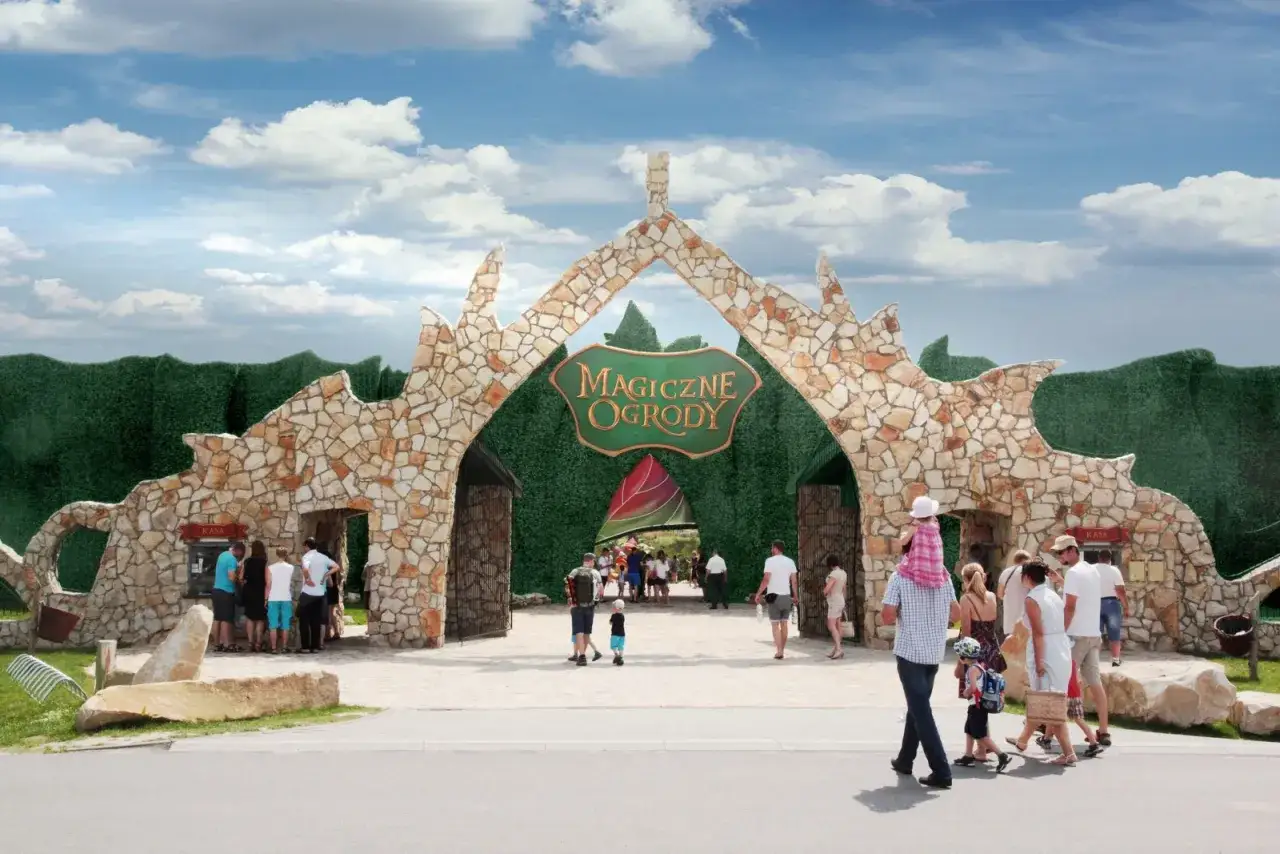 Rodziny wchodzą do Magicznych Ogrodów, planując wakacje na raty. Kamienna brama zaprasza do krainy zabawy i przygód.