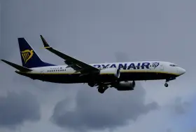 Samolot Ryanair z logo na ogonie leci na tle pochmurnego nieba. Może to być symbol zmiany nazwiska, gdy pasażerowie zmieniają swoje dane przed podróżą.