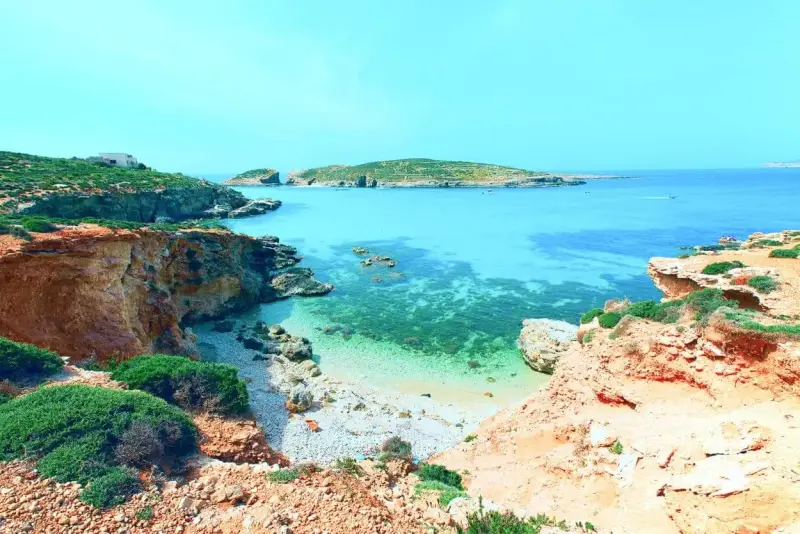Malta last minute tanio! Widok na turkusową zatokę z klifami i zielenią. Idealne miejsce na wakacje.