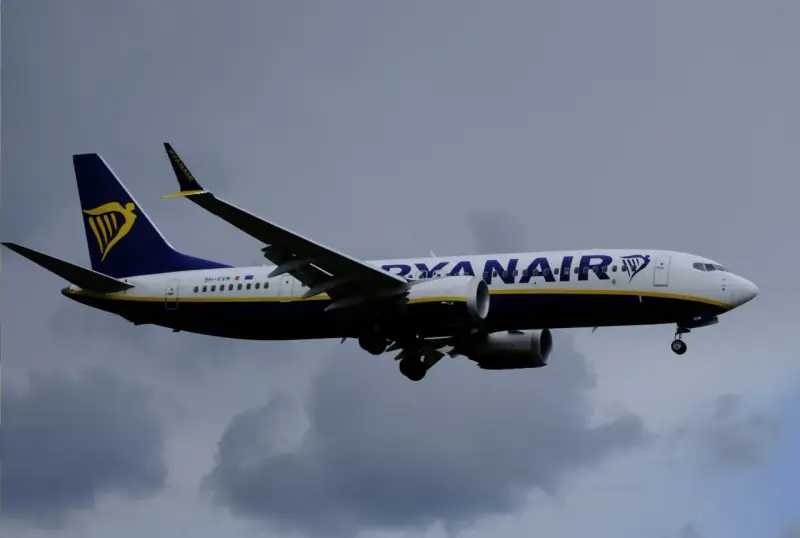 Samolot Ryanair z logo na ogonie leci na tle pochmurnego nieba. Może to być symbol zmiany nazwiska, gdy pasażerowie zmieniają swoje dane przed podróżą.