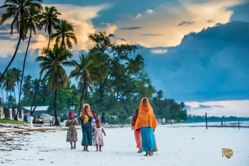 Dzieci na plaży podczas wycieczki na Zanzibar. Palmy i chmury tworzą tło dla tej sceny.